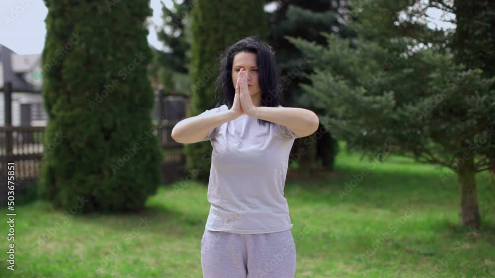 European woman practices yoga in the garden alone. Healthy lifestyle through meditation in the air. European woman practices yoga in the garden alone. Healthy lifestyle through meditation in the air.
