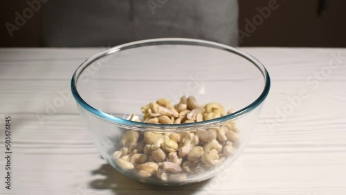 A person is pouring cashews with water