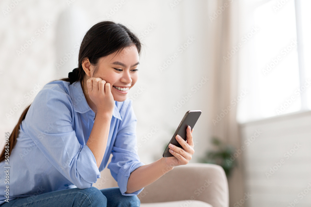 Happy chinese lady using mobile phone at home Happy chinese lady using mobile phone at home