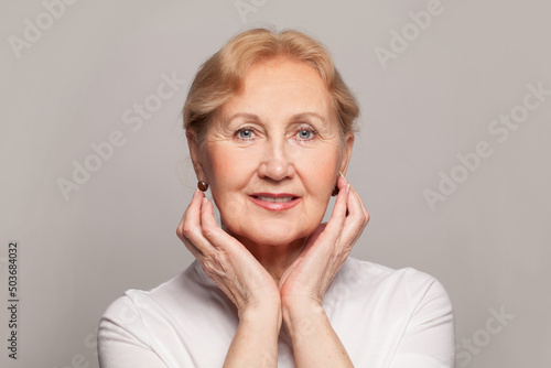 Smiling middle aged mature woman looking at camera, happy old lady posing indoor. Positive single senior female headshot portrait