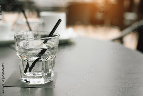 Iced water with black straw in the glass place on wooden in the morning