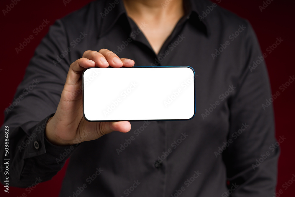 Hand holding a blank screen smartphone while standing on a black background Hand holding a blank screen smartphone while standing on a black background