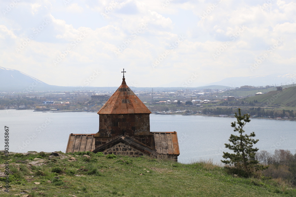 The temple of the ancient Sevanavank monastery on Lake Sevan in Armenia and fragments of the destroyed monastery wall. Holy historical sites in Amenia. The temple of the ancient Sevanavank monastery on Lake Sevan in Armenia and fragments of the destroyed monastery wall. Holy historical sites in Amenia.