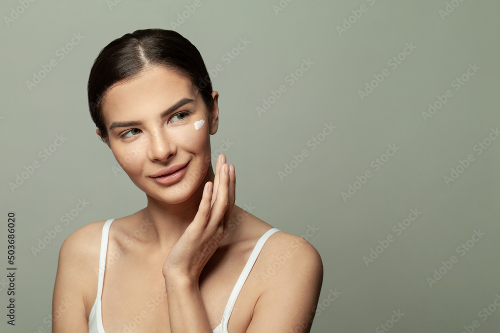 Closeup head shot pleasant beautiful woman applying moisturizing creme on face after shower. Smiling young pretty lady, daily morning routine concept. Closeup head shot pleasant beautiful woman applying moisturizing creme on face after shower. Smiling young pretty lady, daily morning routine concept.