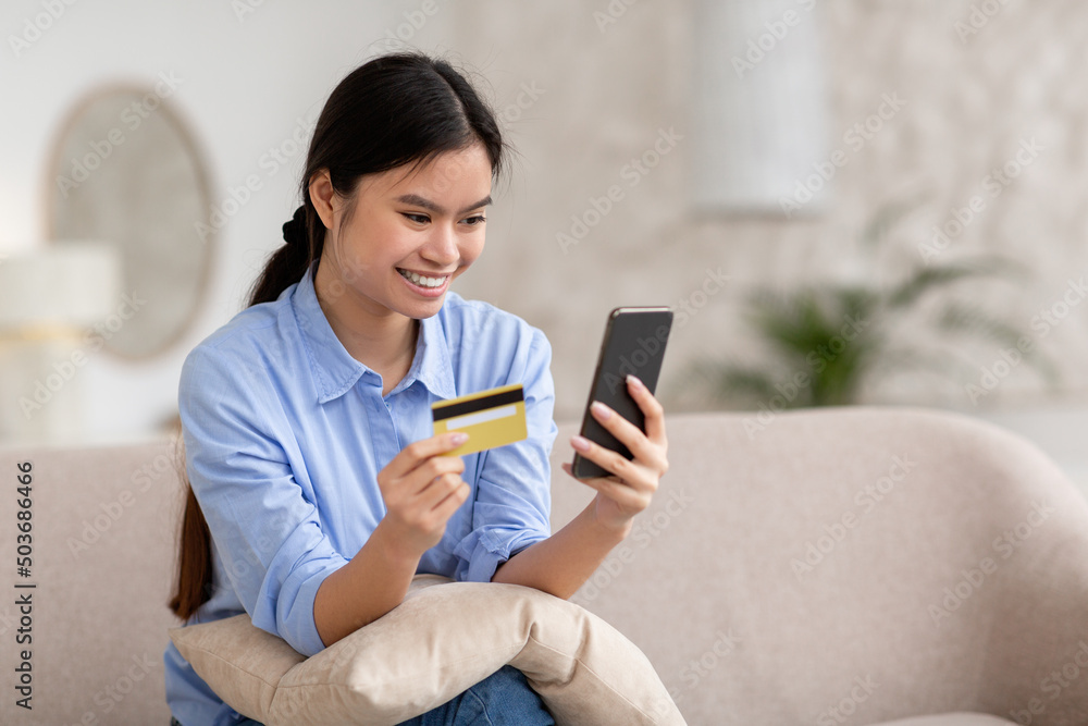 Positive asian woman shopping online, using smartphone and credit card Positive asian woman shopping online, using smartphone and credit card