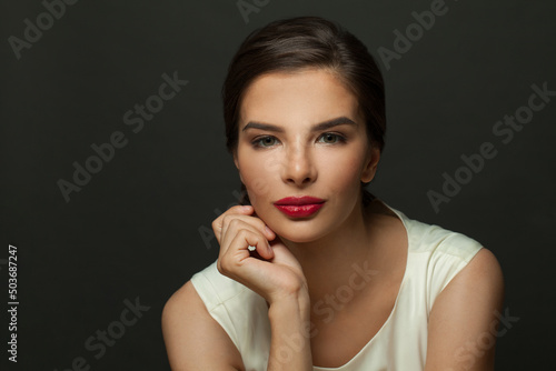 Closeup portrait of attractive woman. Female model  face with red lips makeup on black background