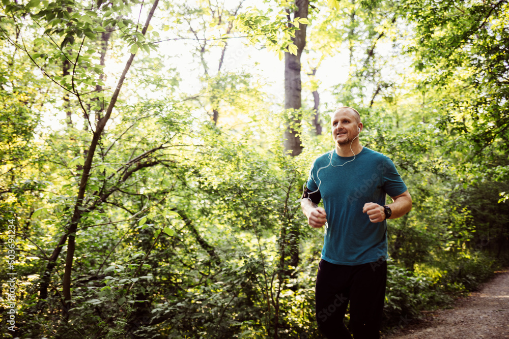 Obraz premium Shot of a young male runner training outdoors. Young athletic man running at park during hot summer morning. Healthy lifestyle concept.