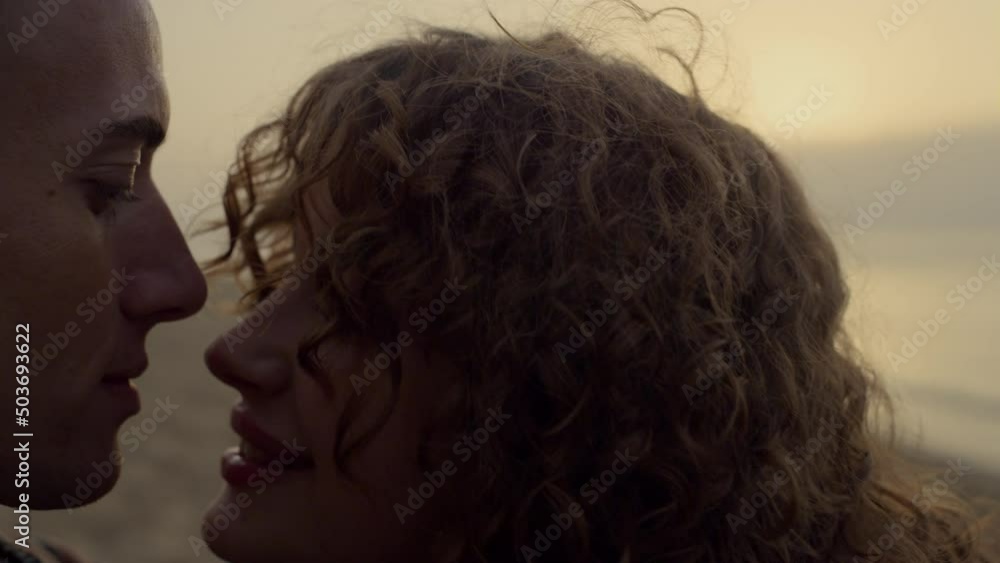 Romantic couple kissing on beach at sunset. Woman face flirting with man at date Romantic couple kissing on beach at sunset. Woman face flirting with man at date