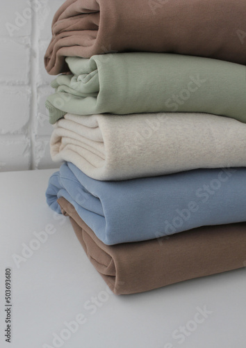 A stack of jumpers in delicate beige, blue and light green tones