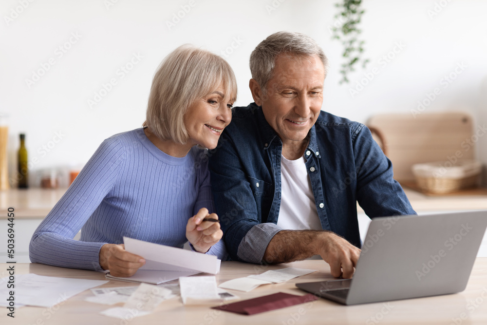 Happy senior couple paying bills online, using computer Happy senior couple paying bills online, using computer
