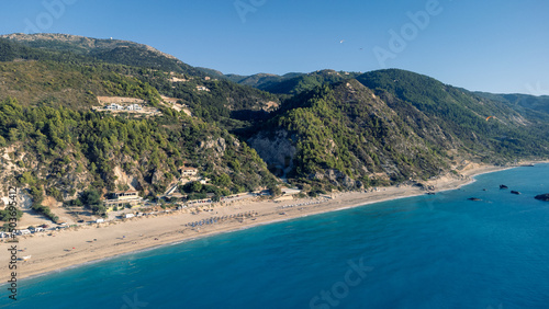 Aerial view of beautiful sandy beach with sunshades and soft turquoise ocean wave. Tropical sea in summer season on Kathisma beach on Lefkada island. © MexChriss