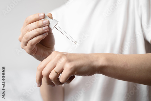 Close up of white woman hand applying oil of essential oil or serum for skin. Self care concept 