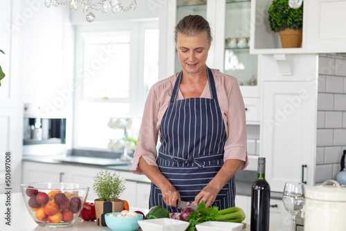 Senior caucasian woman chopping vegetables in kitchen at home