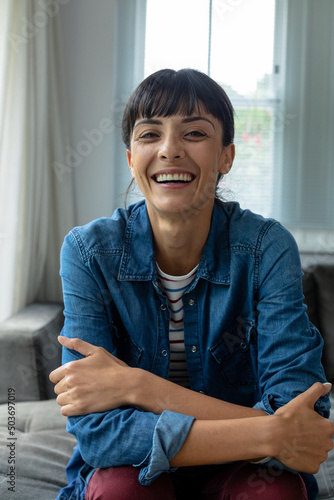 Portrait of cheerful caucasian young woman sitting with arms crossed at home