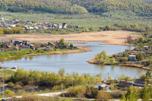 The concept of a healthy lifestyle. View of the village with a lake at the foot of the mountain in early May. Life in the countryside away from civilization