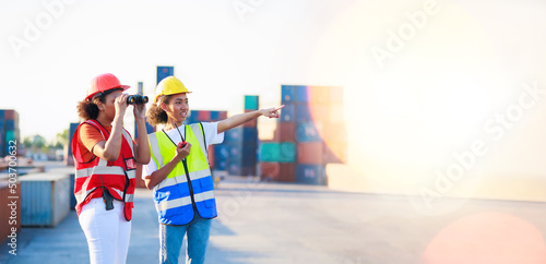 binoculars and walkie talkie. Black female dock worker control loading containers box from cargo at warehouse container yard. Marine and carrier insurance concept.