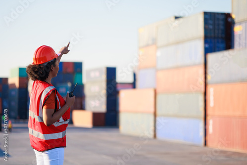 Carta da parati Back view black female dock worker control loading containers box from cargo at warehouse container yard