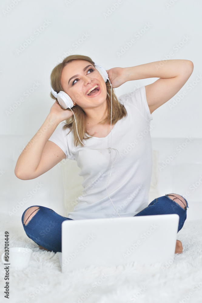 Naklejka premium young woman wearing headphones with laptop computer on the floor
