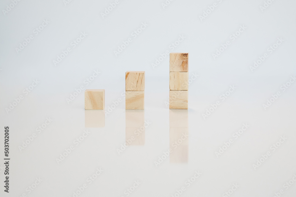 Wooden cubes arranged in column isolated on white background with reflection. Conceptual and symbolic image. Copy space.