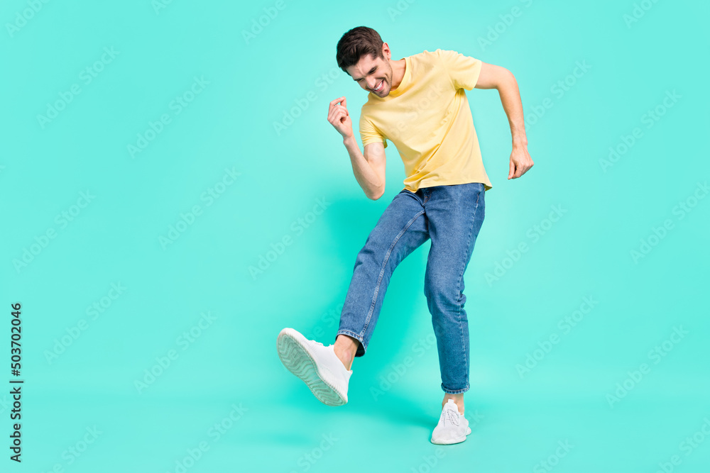 Full length photo of optimistic brunet young guy dance wear t-shirt jeans sneakers isolated on turquoise background Full length photo of optimistic brunet young guy dance wear t-shirt jeans sneakers isolated on turquoise background