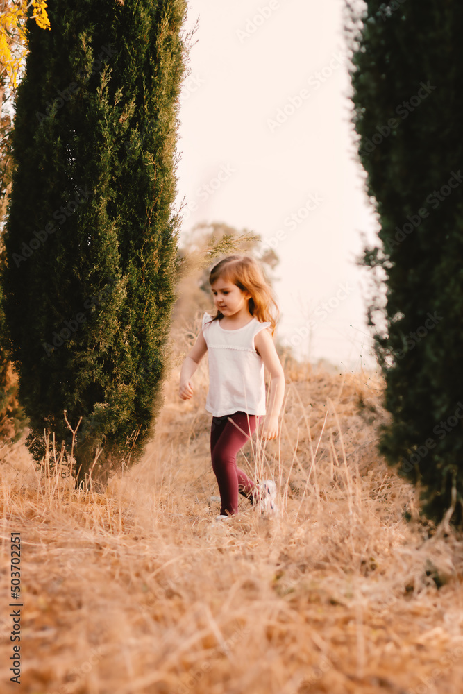 Cute beautiful little girl walking outside in beautiful countryside with spring blooming tree with yellow fresh flowers Cute beautiful little girl walking outside in beautiful countryside with spring blooming tree with yellow fresh flowers