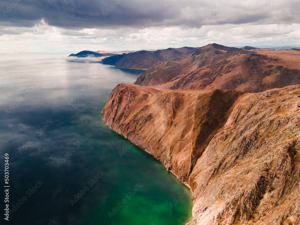 Beautiful coastline of Baikal lake with clear water and mountains. Aerial drone view. Baikal lake, Siberia, Russia. Beautiful spring landscape
