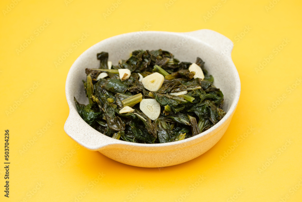 fried spinach with garlic on small light brown bowl fried spinach with garlic on small light brown bowl