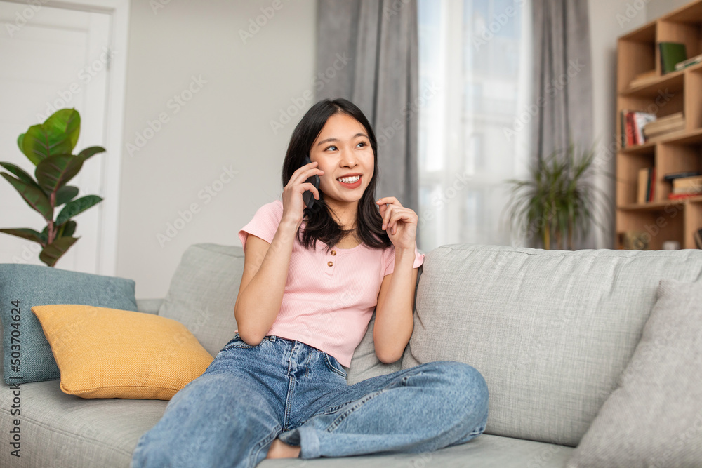 Positive korean woman talking on mobile phone, resting at home and having pleasant conversation, copy space Positive korean woman talking on mobile phone, resting at home and having pleasant conversation, copy space