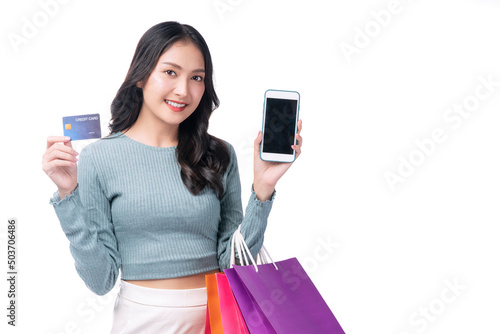 Excited smile Asian woman using mobile phone holding shopping bag show credit card payment banking shopping online. Happiness lady paying debit electronic card shopping advertising. Finance concept.