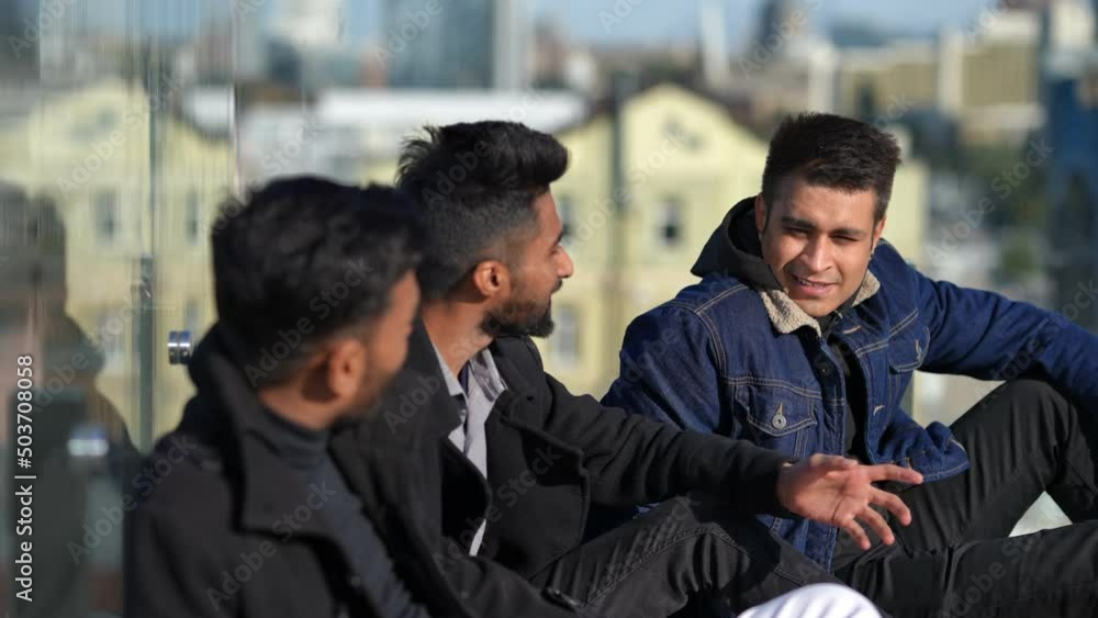 Smiling Middle Eastern man sitting with friends on rooftop talking enjoying weekend leisure. Portrait of confident young handsome guy celebrating bachelor party with mates. Happiness concept Smiling Middle Eastern man sitting with friends on rooftop talking enjoying weekend leisure. Portrait of confident young handsome guy celebrating bachelor party with mates. Happiness concept