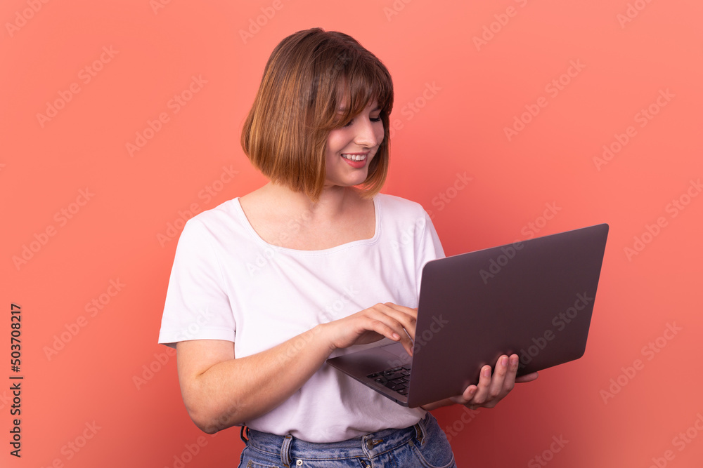 Portrait of attractive amazed cheerful girl agent broker using laptop having fun isolated over pink pastel color background Portrait of attractive amazed cheerful girl agent broker using laptop having fun isolated over pink pastel color background