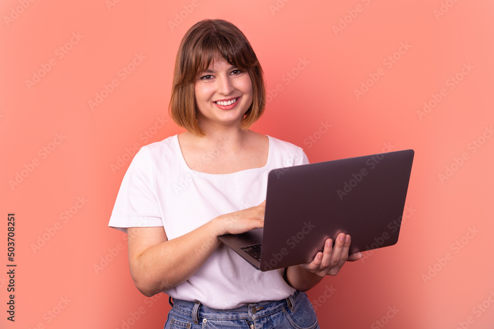 Portrait of attractive amazed cheerful girl agent broker using laptop having fun isolated over pink pastel color background Portrait of attractive amazed cheerful girl agent broker using laptop having fun isolated over pink pastel color background