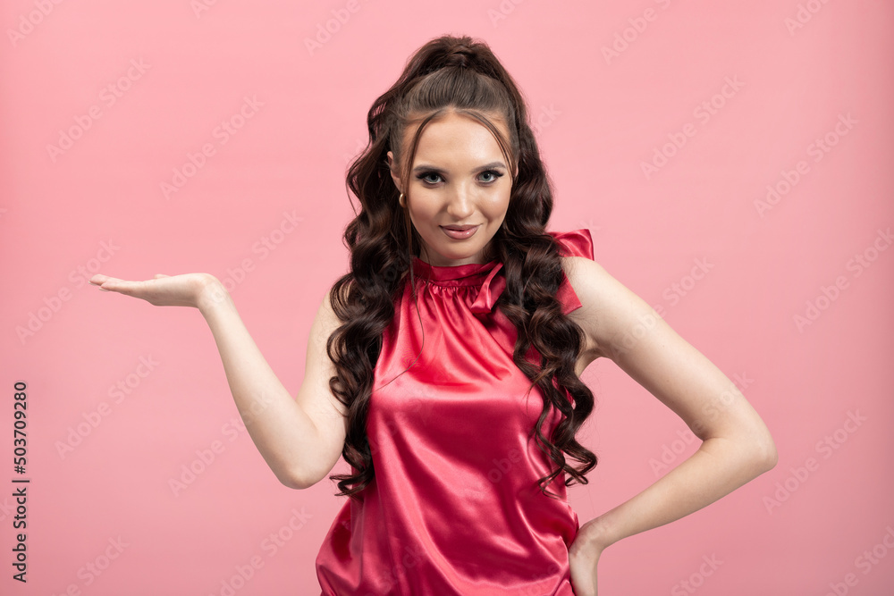 The shocked woman looks to the side points hand she is excited surprised. Elegant young girl on pink background. The shocked woman looks to the side points hand she is excited surprised. Elegant young girl on pink background.