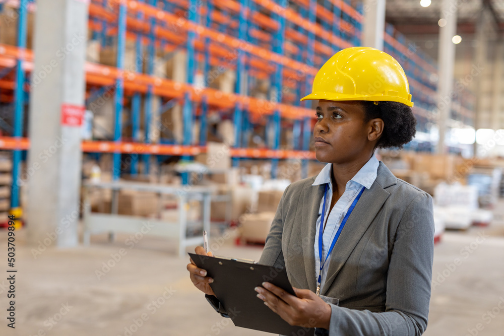 African american young female manager holding clipboard looking away while working in warehouse African american young female manager holding clipboard looking away while working in warehouse