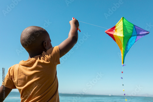 African american boy enjoying kite flying against blue sky on sunny day