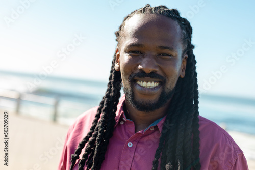 Portrait of smiling african american man with long braided black hair on sunny day