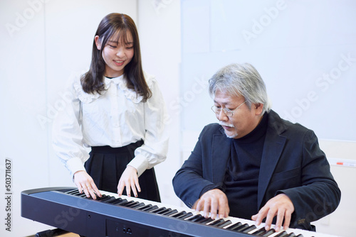 ピアノを教える若い女性と教わる男性 photo