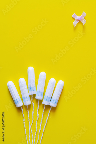 top view of tampons and bow on yellow background with copy space.