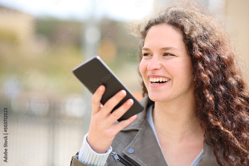 Happy woman laughing using voice recognition on phone Happy woman laughing using voice recognition on phone
