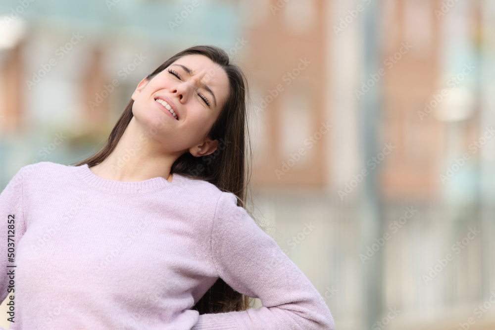 Teen complaining about back ache in the street Teen complaining about back ache in the street