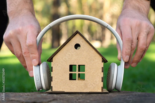 Man placing white headphones on a toy house model