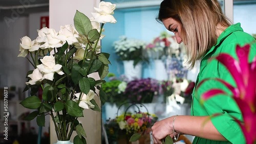 Woman in a flower salon prepares flowers to make a bouquet