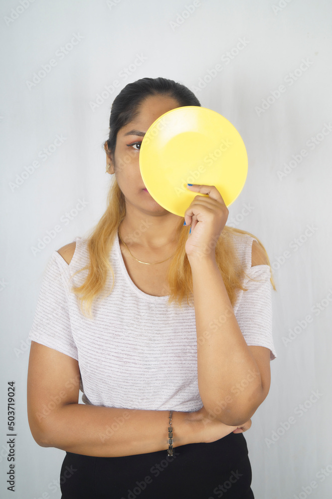 Young adult holding empty plate while standing in front of white background Young adult holding empty plate while standing in front of white background