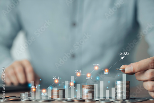 Businessman hand putting coin stack for saving money, Stock Market finance and Investments growing with businessman investor 2022, management of Business finance background.