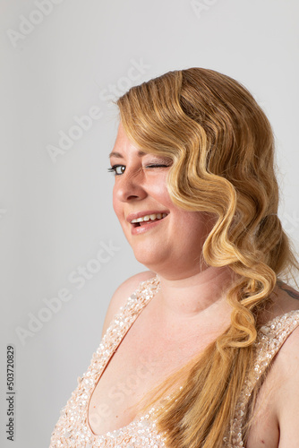 Portrait of a beautiful woman in her 40s. Long red blonde wavy hair with beautiful waves. The portrait is in studio on a white background.