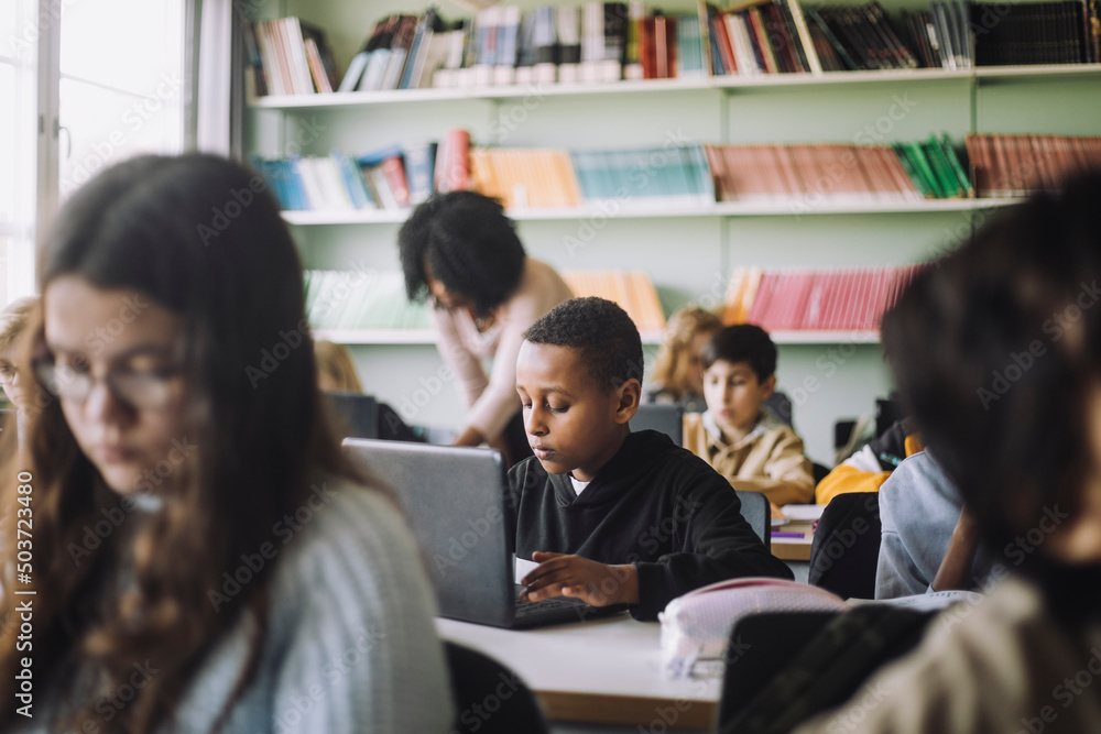 Boy using laptop while e-learning in classroom Boy using laptop while e-learning in classroom