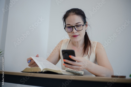Asian woman sits and makes notes while studying the bible. Concept of hope, faith, christianity, religion, church online.