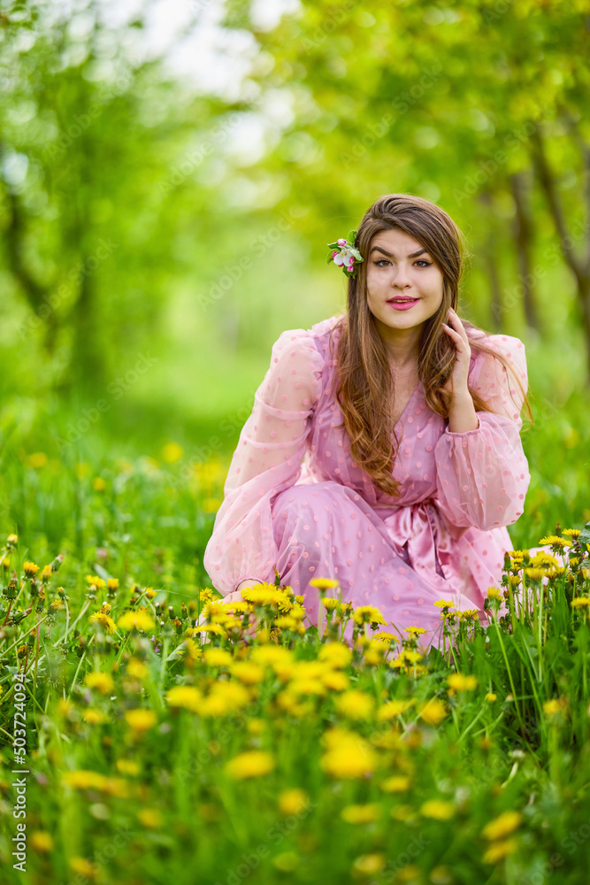a young woman in a pink dress posing next to a blossoming apple, spring portrait. a young woman in a pink dress posing next to a blossoming apple, spring portrait.