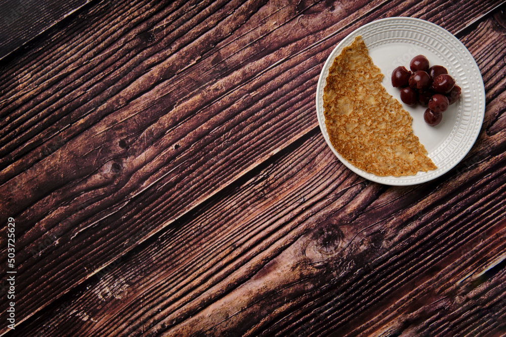 Taken from above flat lay picture of half a pancake with canned black cherries copy space left. Taken from above flat lay picture of half a pancake with canned black cherries copy space left.