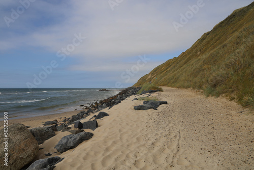 Empty path next to the sandy coastline of Lonstrup under a blue cloudy sky during the daytime photo